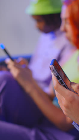 Close-Up-Vertical-Video-Studio-Shot-Of-Group-Of-Young-Gen-Z-Friends-Gaming-Streaming-And-Using-Social-Media-On-Mobile-Phones